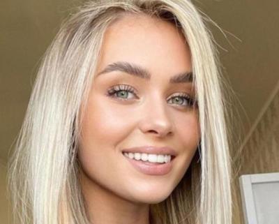 Een jonge vrouw met lang, golvend blond haar en een bloemenkroon kijkt kalm vooruit. Ze wordt omringd door spirituele symbolen zoals Lenormandkaarten,